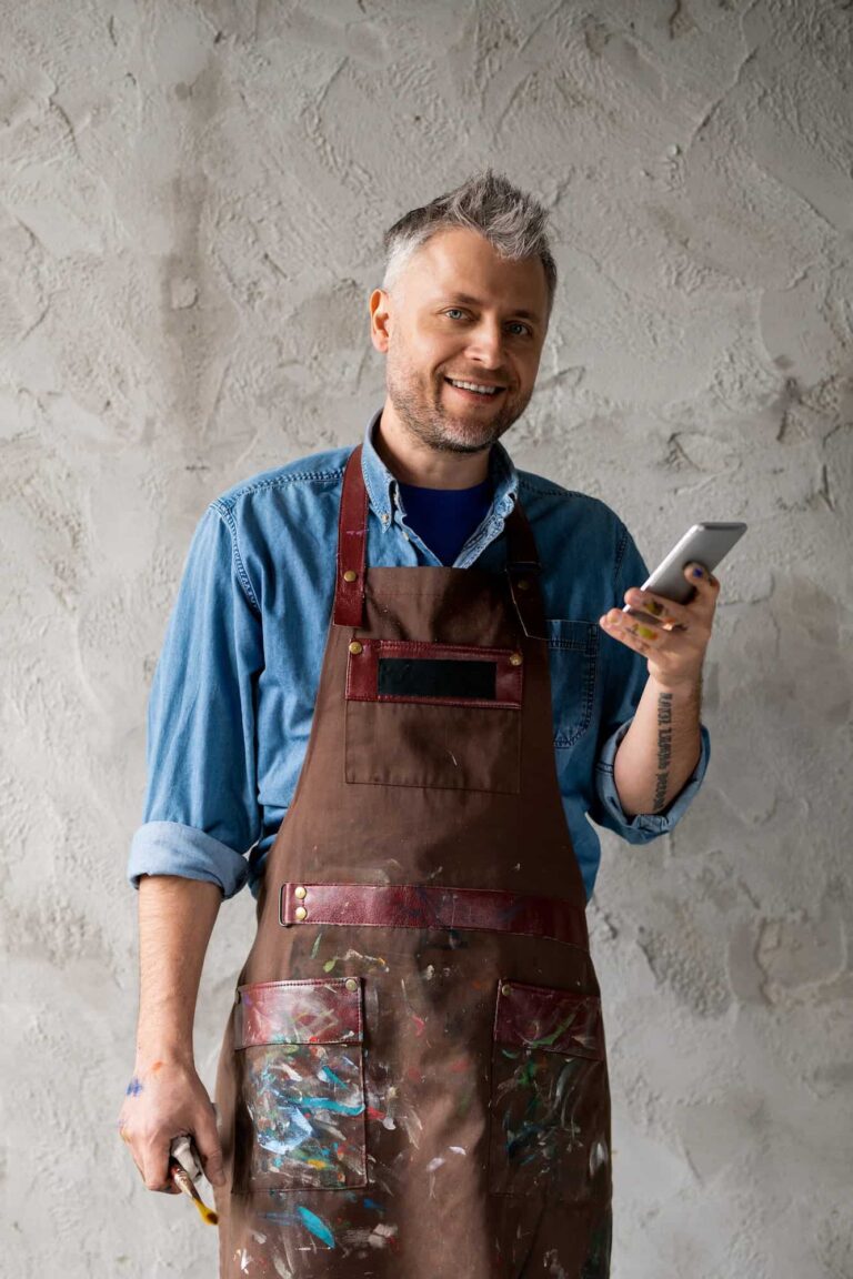 happy-and-successful-painter-with-smartphone-and-paintbrush