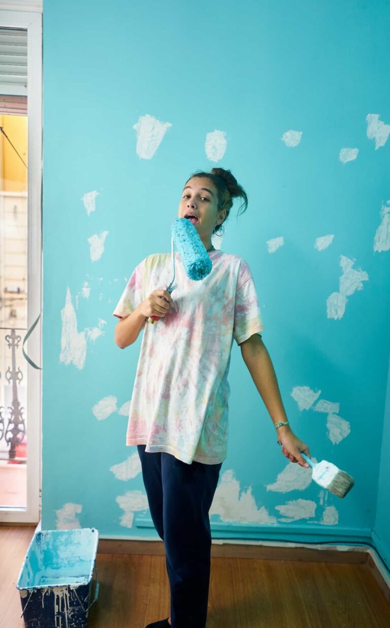 happy-woman-painting-interior-wall-with-paint-roller-in-new-house